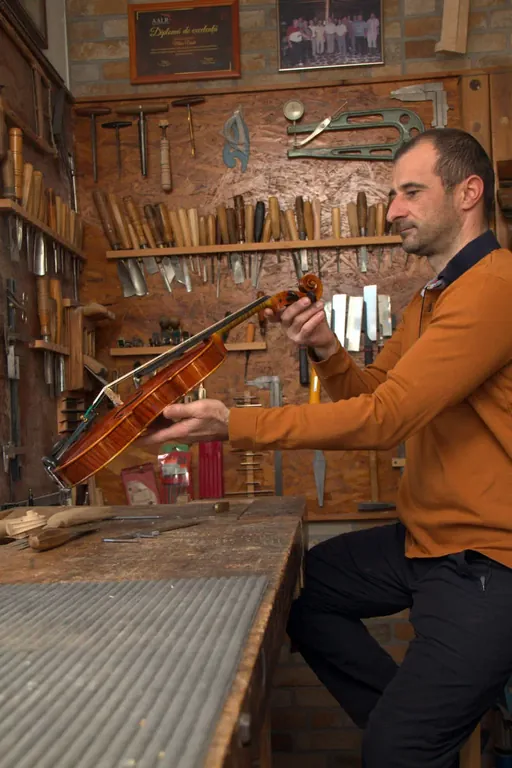 Aurelian inspectând o vioară finisată în atelier